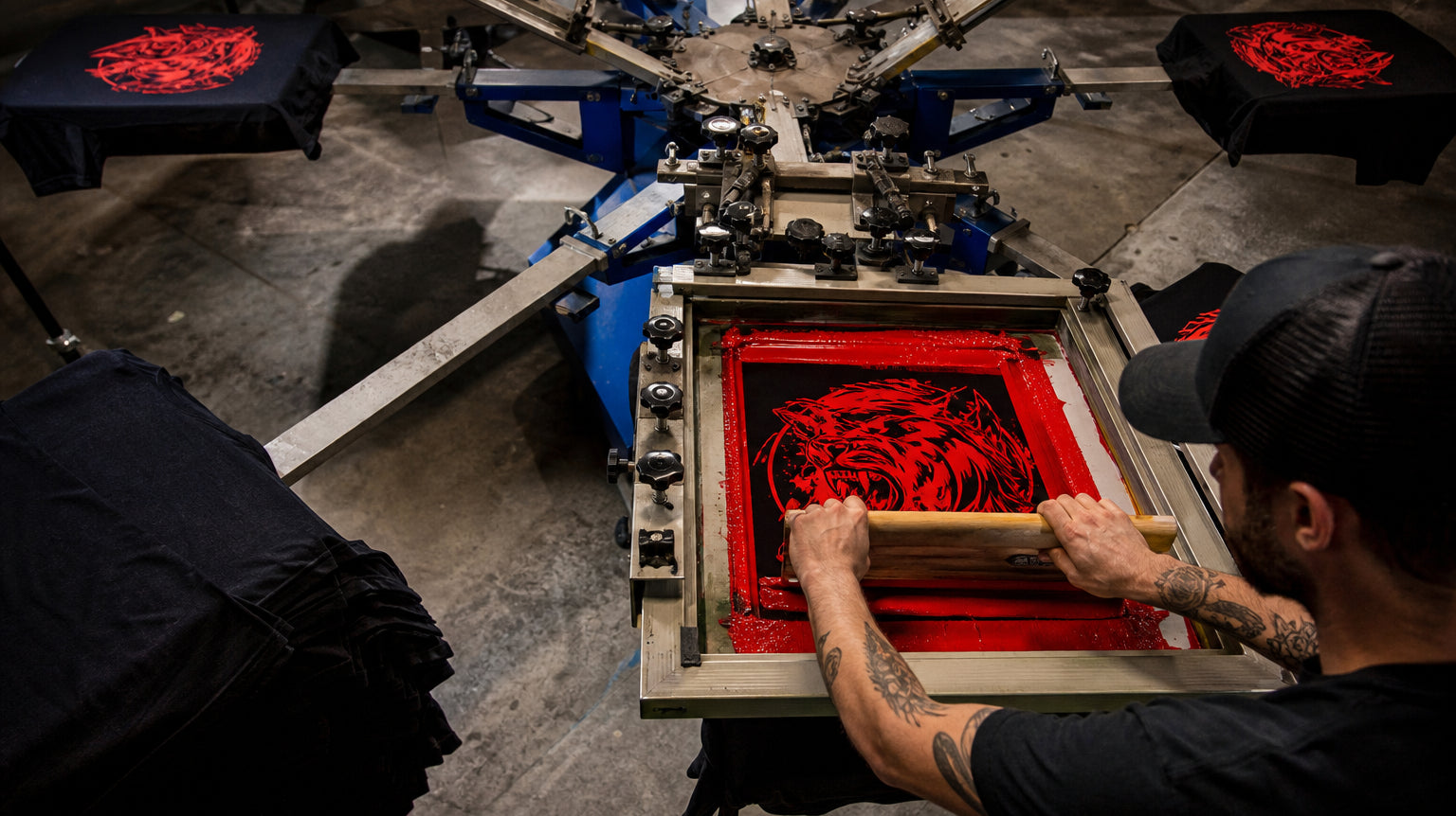 Screen printing press in action with red ink being pulled across a screen β The Printing Needle Garden Grove