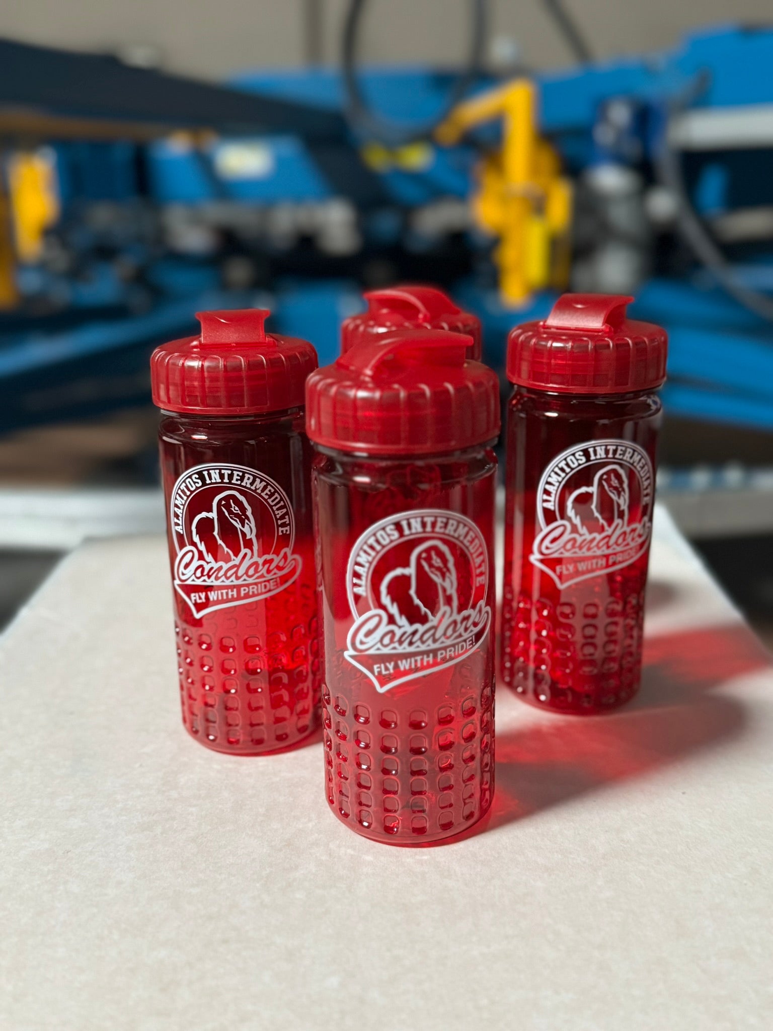Three red water bottles with impression of a logo on a white surface