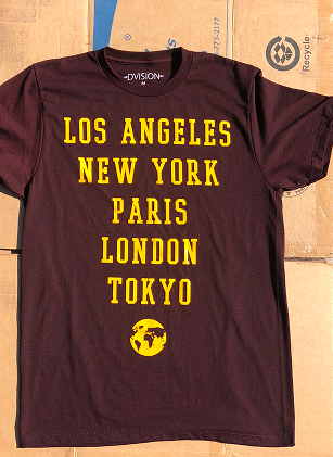 Maroon t-shirt with yellow text and globe graphic on a wooden surface